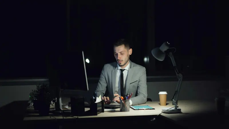 Profissional de terno trabalhando ao computador em escritório, à noite