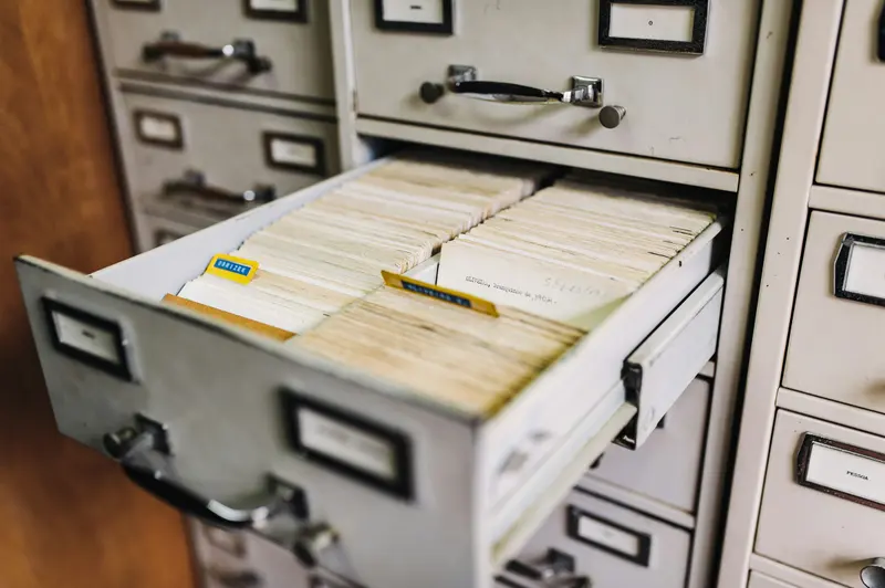 Gaveta de arquivo de aço aberta, cheia de fichas e pastas de documentos