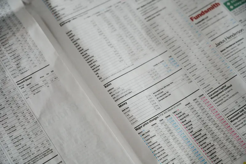 Página de jornal financeiro com tabelas de números e cotações